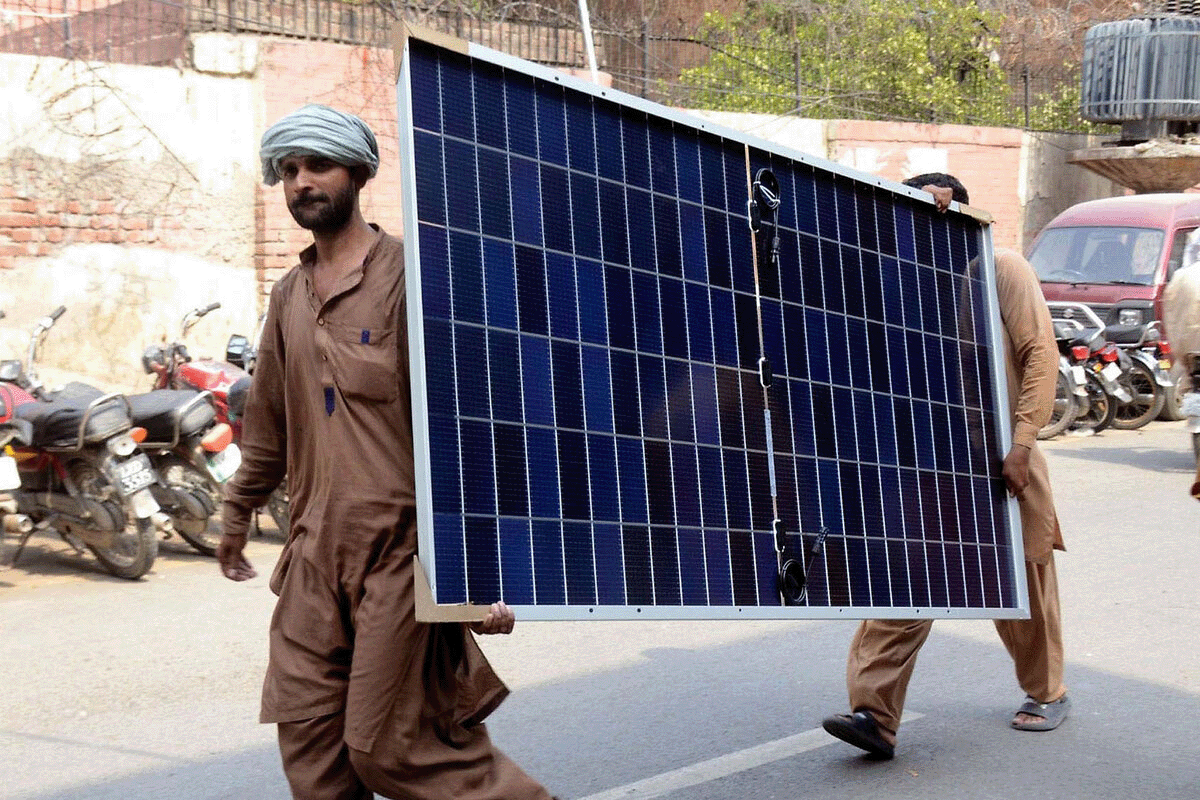 Two men carrying a Chinese Solar panel in Pakistan